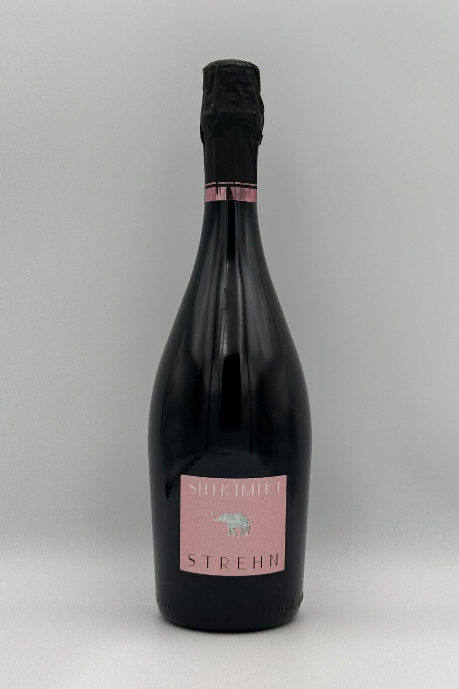 A bottle of Stehn Still Life bitter sparkling wine with a dark glass body, black foil, and a pink label, set against a neutral gray background.